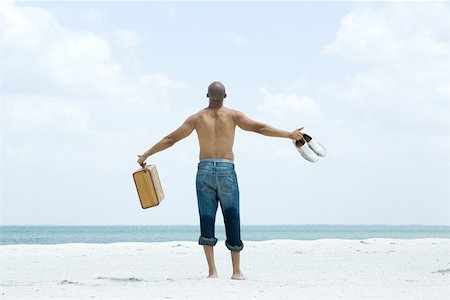 simsearch:696-03402108,k - Man standing on beach holding out suitcase and shoes, rear view Stock Photo - Premium Royalty-Free, Code: 696-03402093