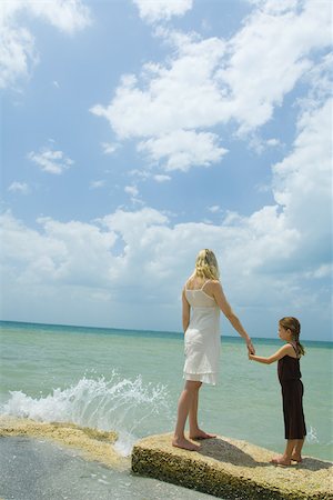 simsearch:696-03401543,k - Mother and daughter standing by ocean as waves crash, holding hands and facing horizon, full length Foto de stock - Sin royalties Premium, Código: 696-03402129