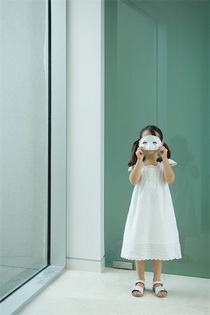 standing person covering eyes - Little girl holding mask in front of eyes Stock Photo - Premium Royalty-Free, Code: 696-03402135