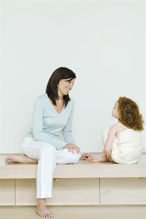 Woman and little girl sitting together, smiling at each other, full length Stock Photo - Premium Royalty-Free, Code: 696-03402131