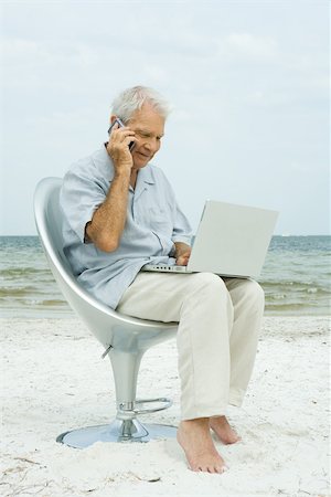 Senior man using cell phone and laptop, sitting in chair on beach Stock Photo - Premium Royalty-Free, Code: 696-03402161