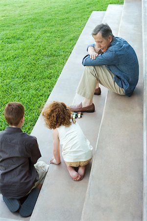 simsearch:695-03378542,k - Grandfather and two grandchildren playing with toy cars together on stairs, high angle view Foto de stock - Sin royalties Premium, Código: 696-03402179