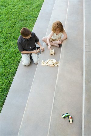 Brother and sister playing with blocks on stairs, high angle view Stock Photo - Premium Royalty-Free, Code: 696-03402173