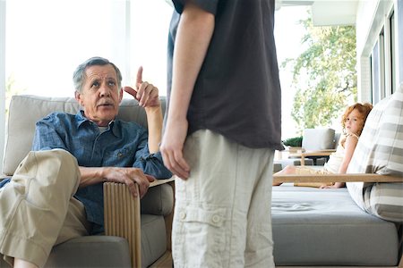 scolding - Senior homme assis dans le fauteuil, regardant vers le haut de petit-fils, recadrée vue Photographie de stock - Premium Libres de Droits, Code: 696-03402182