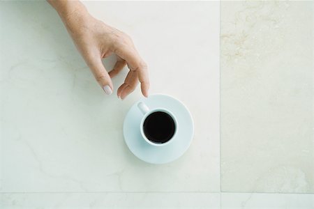 Hand reaching for coffee cup, viewed from directly above Stock Photo - Premium Royalty-Free, Code: 696-03402234