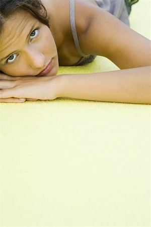 simsearch:695-03378068,k - Teenage girl with head resting on arms, looking at camera, cropped view Fotografie stock - Premium Royalty-Free, Codice: 696-03402255