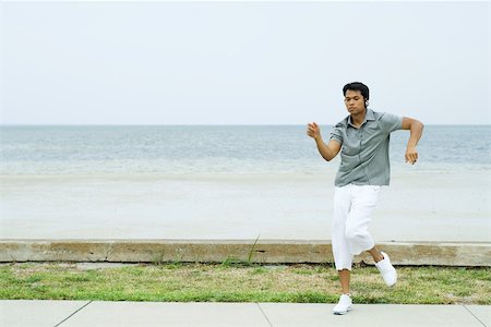 Man listening to headphones and dancing at the beach, full length Stock Photo - Premium Royalty-Free, Code: 696-03402275