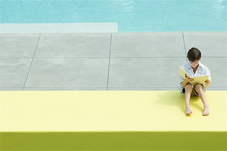 Boy sitting by swimming pool, reading book Foto de stock - Sin royalties Premium, Código: 696-03402277