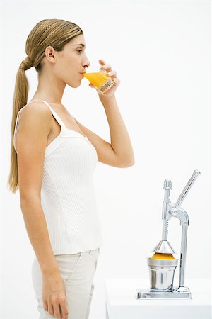 presse-agrumes - Jeune femme debout devant le presse-agrumes, boire des jus d'orange fraîchement pressé Photographie de stock - Premium Libres de Droits, Code: 696-03402375