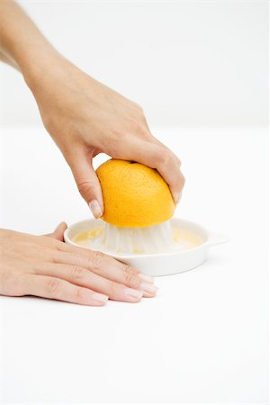 Woman squeezing orange with citrus press, cropped view of hands Stock Photo - Premium Royalty-Free, Code: 696-03402370