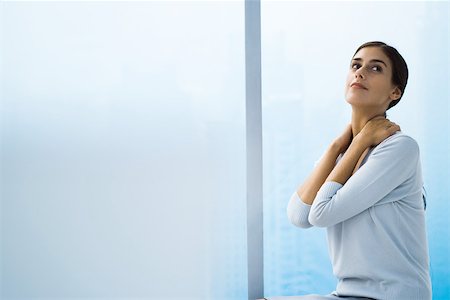 Woman with hands behind neck, looking up Stock Photo - Premium Royalty-Free, Code: 696-03402413