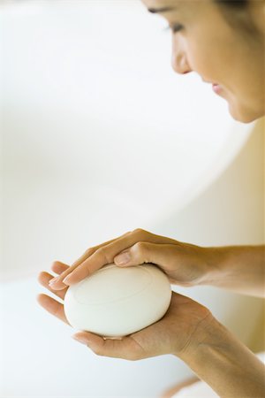 Woman holding bar of soap in hands, looking down, cropped view Stock Photo - Premium Royalty-Free, Code: 696-03402447