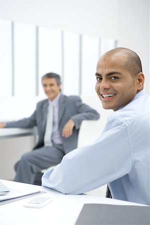 simsearch:633-01837165,k - Two businessmen sitting in office, smiling at camera Fotografie stock - Premium Royalty-Free, Codice: 696-03402455