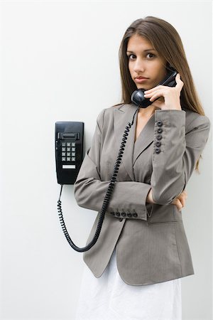 falta de comunicação - Teen girl using landline phone, looking at camera Foto de stock - Royalty Free Premium, Número: 696-03402485