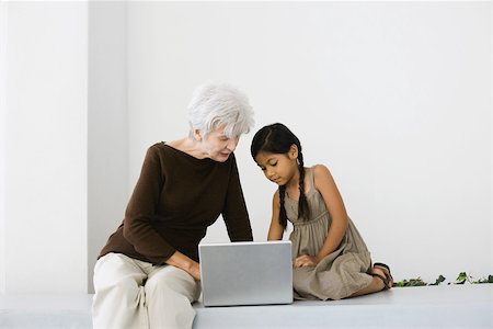 Senior woman and granddaughter using laptop together, looking down Stock Photo - Premium Royalty-Free, Code: 696-03402481