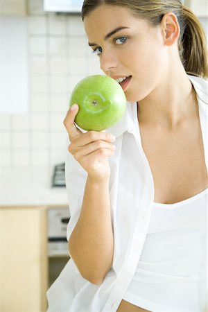 flirt women open mouth - Young woman pretending to bite apple, smiling at camera Stock Photo - Premium Royalty-Free, Code: 696-03402516