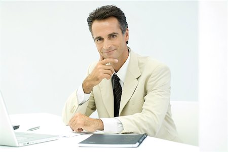 Business executive sitting at desk, smiling at camera, portrait Stock Photo - Premium Royalty-Free, Code: 696-03402549