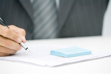 pen contract - Man with adhesive note and document, holding pen, cropped view Stock Photo - Premium Royalty-Free, Code: 696-03402576