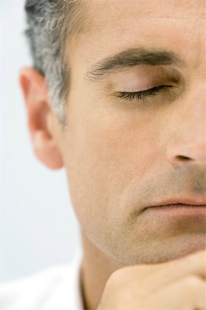 Man with eyes closed, hand under chin, cropped view Stock Photo - Premium Royalty-Free, Code: 696-03402578