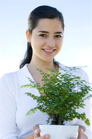 simsearch:633-02066101,k - Jeune femme tenant une plante en pot, souriant à la caméra Photographie de stock - Premium Libres de Droits, Code: 696-03402594