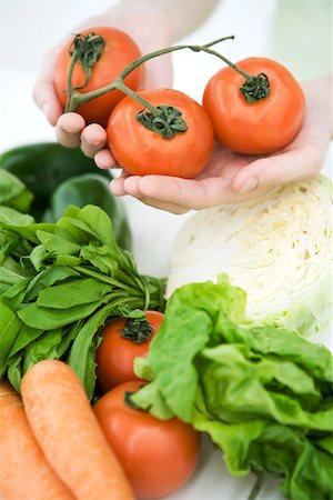 simsearch:649-06432399,k - Hands holding vine tomatoes, assorted fresh vegetables in foreground Foto de stock - Sin royalties Premium, Código: 696-03402601