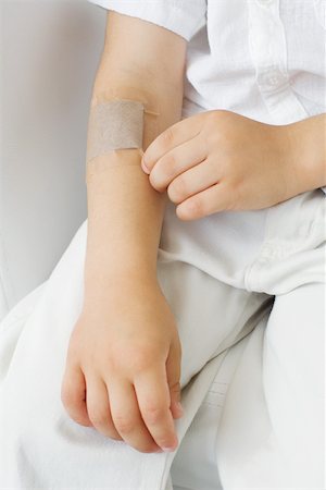 simsearch:614-03020295,k - Little boy picking at adhesive bandage on his arm, cropped view Fotografie stock - Premium Royalty-Free, Codice: 696-03402611