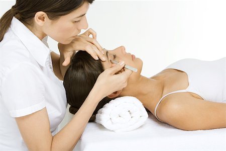 Woman lying on her back having her eyebrows plucked by a beautician Foto de stock - Sin royalties Premium, Código: 696-03402621