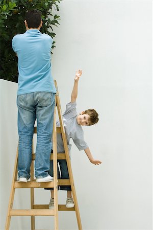 father son gardening - Father and son standing on ladder, boy pretending to be a plane Stock Photo - Premium Royalty-Free, Code: 696-03402631