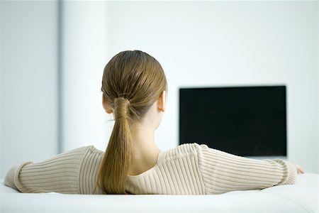 Woman watching TV, rear view Stock Photo - Premium Royalty-Free, Code: 696-03402724