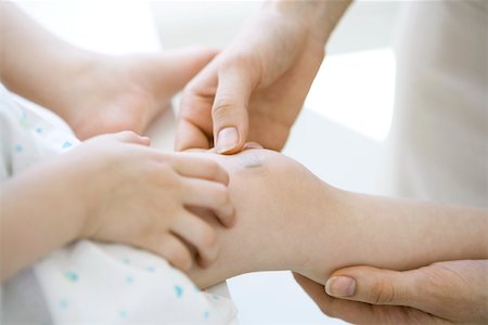 simsearch:633-02645553,k - Adult placing adhesive bandage on child's knee, cropped view Stock Photo - Premium Royalty-Free, Code: 696-03402746