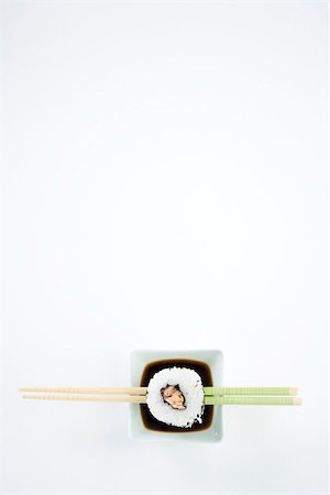 sushi rice - Single piece of maki sushi on chopsticks over dish of soy sauce, overhead view Stock Photo - Premium Royalty-Free, Code: 696-03402756