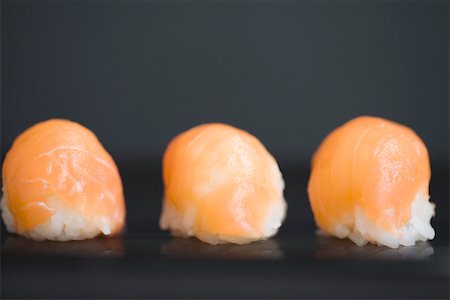 simsearch:6115-06732903,k - Three pieces of salmon nigiri sushi with dark background, close-up Stock Photo - Premium Royalty-Free, Code: 696-03402778