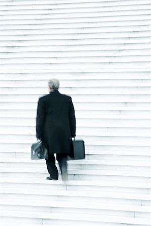 política en la oficina - Businessman carrying two heavy bags slowly going up stairs outdoors Foto de stock - Sin royalties Premium, Código: 696-03402960