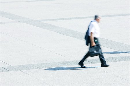 simsearch:695-05764648,k - Businessman with jacket on shoulder walking across public square Foto de stock - Sin royalties Premium, Código: 696-03402977