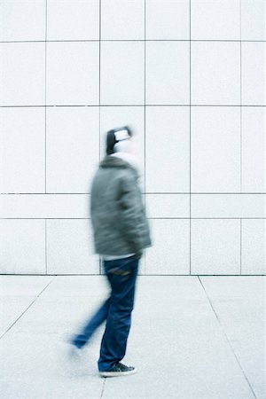 simsearch:696-03402939,k - Man walking with hands in pockets on sidewalk Stock Photo - Premium Royalty-Free, Code: 696-03402970