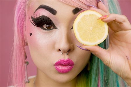 simsearch:693-05552819,k - Woman holding slice of lemon in front of her eyes Foto de stock - Sin royalties Premium, Código: 693-05552784