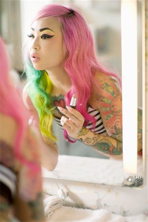 Reflection of a young woman in mirror applying lipstick Foto de stock - Sin royalties Premium, Código: 693-05552802