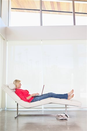 Pleine longueur de femme couchée sur une chaise longue avec ordinateur portable Photographie de stock - Premium Libres de Droits, Code: 693-05552970