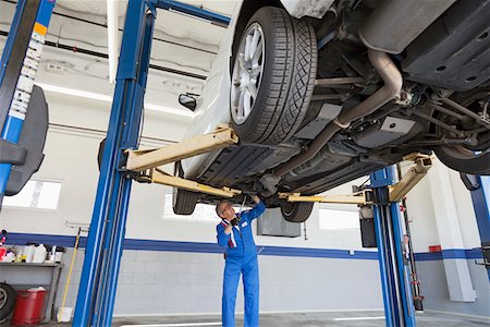Low angle view of mechanic working under car Stock Photo - Premium Royalty-Free, Code: 693-05794044