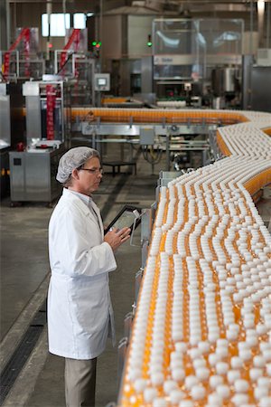 Man inspecting orange juice bottles at bottling plant Foto de stock - Sin royalties Premium, Código: 693-05794228