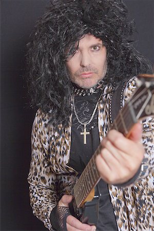 Portrait of middle-aged man wearing leopard skin pattern with guitar over black background Stock Photo - Premium Royalty-Free, Code: 693-05794273