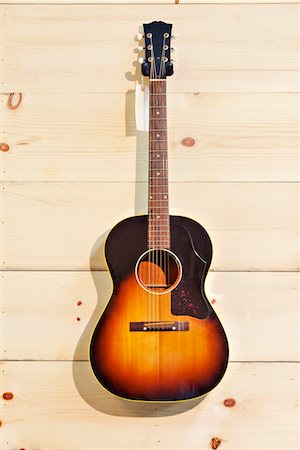 Acoustic guitar with label isolated on a wood grain wall Foto de stock - Royalty Free Premium, Número: 693-05794332