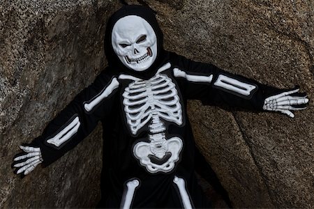 Boy dressed up as skeleton posing on rock Foto de stock - Sin royalties Premium, Código: 693-05794364