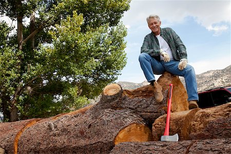 Low angle view of man sitting on a huge tree trunk Stock Photo - Premium Royalty-Free, Code: 693-05794393