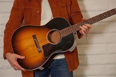 shop to play - Close-up of mid adult man's torso holding guitar Stock Photo - Premium Royalty-Free, Code: 693-05794443