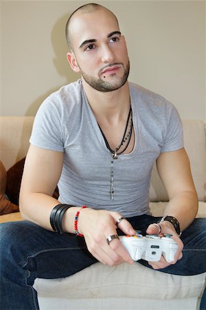 Casual young man playing video game Fotografie stock - Premium Royalty-Free, Codice: 693-05794483