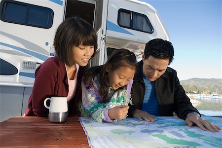 Two parents and daughter looking at map on picnic table outside RV Stock Photo - Premium Royalty-Free, Code: 693-06014000