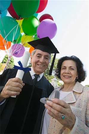 picture of person receiving diploma - Senior graduate receiving present from wife outside, low angle view Stock Photo - Premium Royalty-Free, Code: 693-06014187