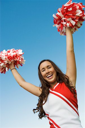 female teen in track and field - Smiling Cheerleader rising pom-poms, (portrait), (low angle view) Stock Photo - Premium Royalty-Free, Code: 693-06014237