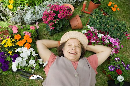 Senior woman lying on ground among flowers, smiling, (overhead view) Stock Photo - Premium Royalty-Free, Code: 693-06014338
